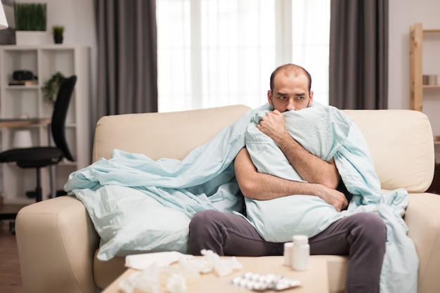 Kranker Mann mit Schüttelfrost während der Quarantäne in Blacket gehüllt.