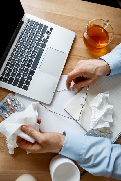 Kranker Mann während der Arbeit im Büro, Geschäftsmann erkältete, saisonale Grippe.