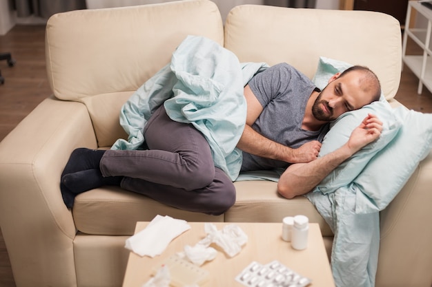 Kranker und depressiver Mann, der während der Selbstisolation auf dem Sofa liegt.