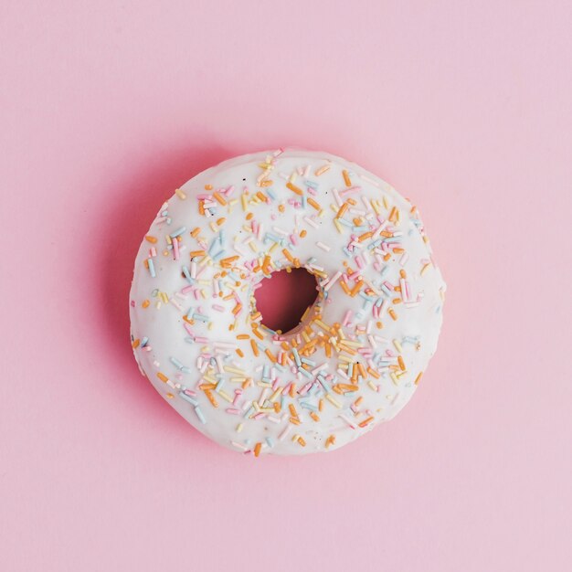 Krapfen mit Belag besprühen auf rosa Hintergrund