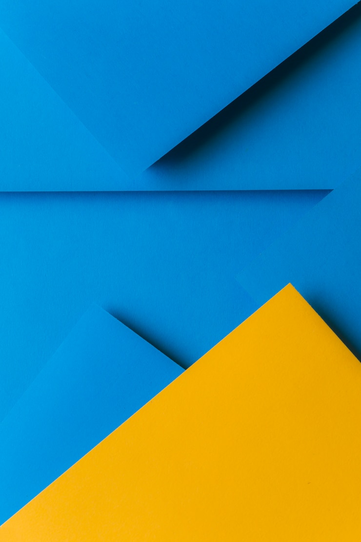 Kostenlose Foto kreative anordnung für gelbes und blaues farbiges papier, das einen abstrakten hintergrund schafft