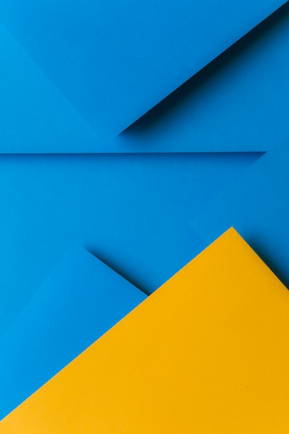 Kreative Anordnung für gelbes und blaues farbiges Papier, das einen abstrakten Hintergrund schafft