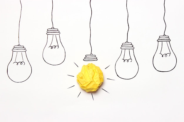 Kreative konzeptidee bemalte glühbirne mit einem zerknitterten gelben papierball