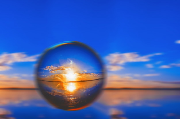 Kreative Linsenballfotografie des Sonnenlichts am Horizont mit Wolken herum im blauen Himmel