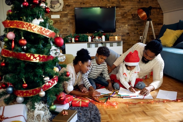 Kreative schwarze Familienfärbung auf dem Papier, während sie den Weihnachtstag zu Hause verbringen