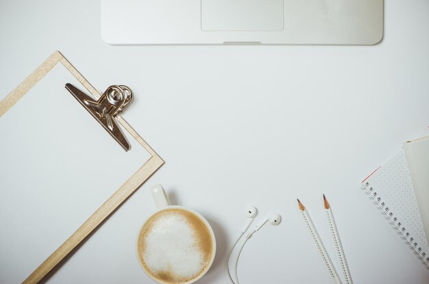 Kreativer Desktop mit Laptop-Kaffee und Schreibwaren auf weißem Tisch Draufsicht Flache Lage