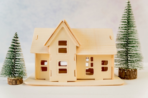 Kreatives Haus mit grünen Weihnachtsbäumen auf strukturiertem Hintergrund