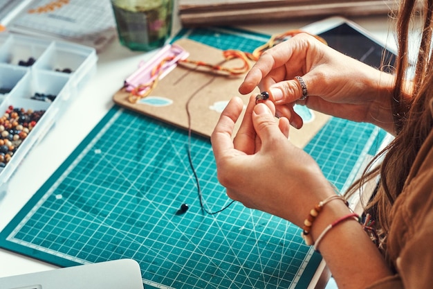 Kostenloses Foto kreatives mädchen hat ein sehr interessantes hobby - sie stellt schmuck aus perlen und steinen her.