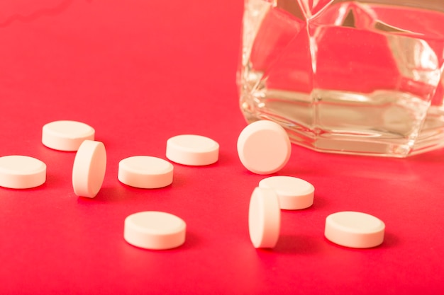 Kostenloses Foto kreisförmige weiße tabletten mit glas wasser auf dunklem hintergrund