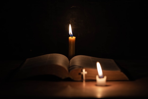 Kreuzen Sie mit Bibel und Kerze auf einem alten Eichenholztisch.