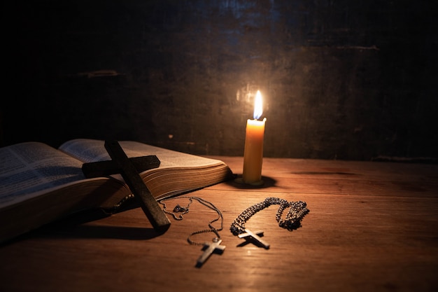 Kreuzen Sie mit Bibel und Kerze auf einem alten Eichenholztisch.