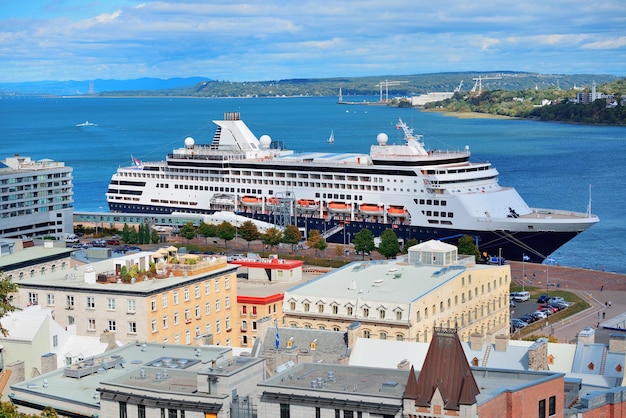 Kreuzfahrtschiff im Fluss in Quebec City mit blauem Himmel und historischen Gebäuden.