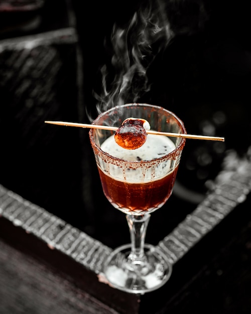 Kostenloses Foto kristallglas eines heißen cocktails, garniert mit geröstetem marshmallow am spieß