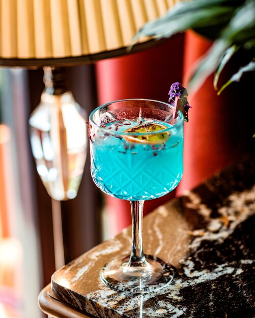 Kristallglas mit blauem Cocktail, garniert mit getrockneter Orangenscheibe