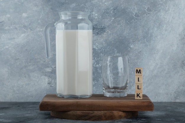 Krug Milch und Glas Wasser auf Holzbrett.