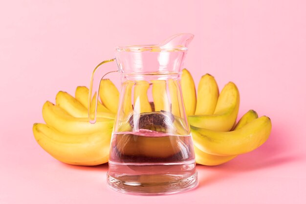 Krug Wasser mit Bananen im Hintergrund