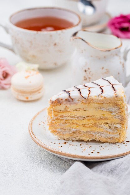 Kuchen auf Teller mit Tee und Macarons