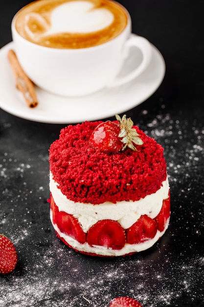 Kuchen mit Erdbeeren und Tasse Cappuccino auf dem Tisch