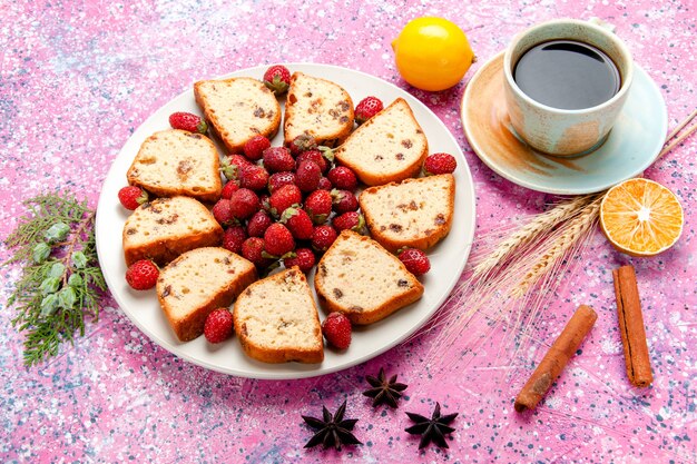 Kuchenscheiben mit halber Draufsicht mit frischen Erdbeeren und einer Tasse Kaffee auf rosa Schreibtischkuchen backen süßen Keksfarbkuchen-Zuckerkeks