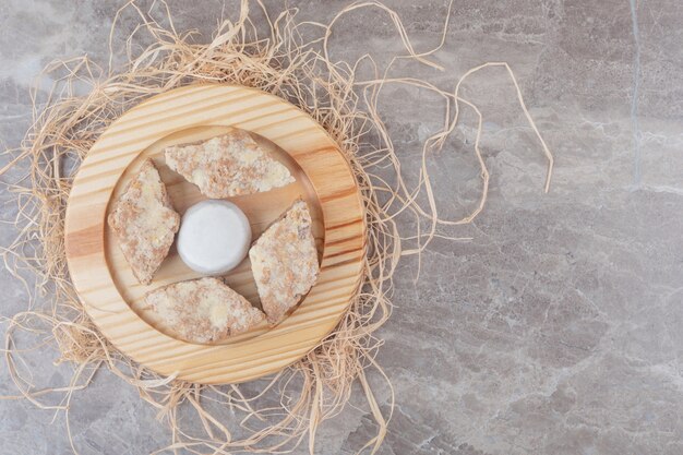 Kuchenscheiben um einen mit Vanillepulver beschichteten Keks auf einem Holzteller auf Marmor