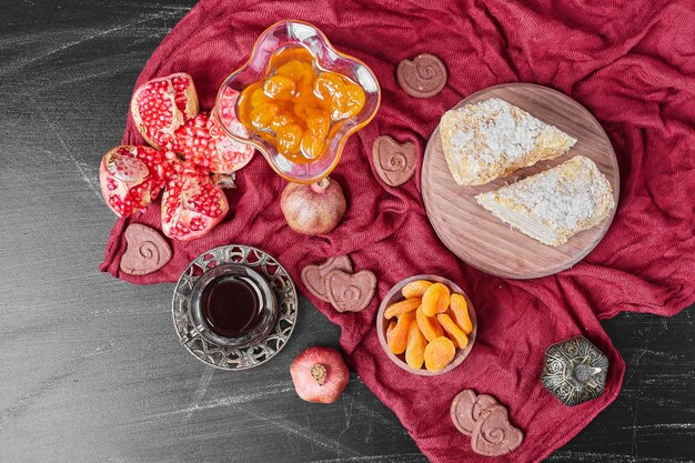 Kuchenscheiben und Konfekt auf rotem Handtuch mit Tee.