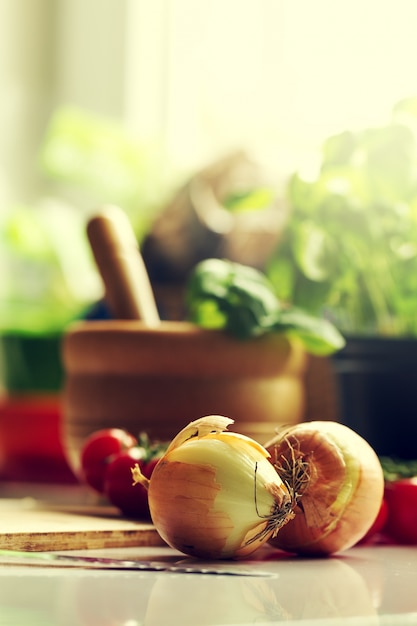 Küche Hintergrund Kochen Essen Konzept. Zwiebel auf dem Tisch. Gemüse auf dem Tisch. Kochvorgang Toning