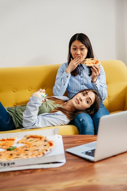 Kühlende Mädchen, die Film aufpassen und Pizza essen