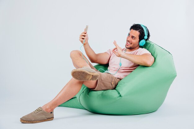 Kühler Mann auf Couch mit Selfie mit Smartphone