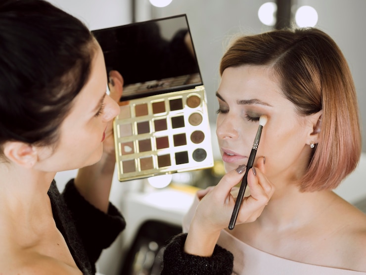 Kostenlose Foto künstler, der make-up auf modell anwendet