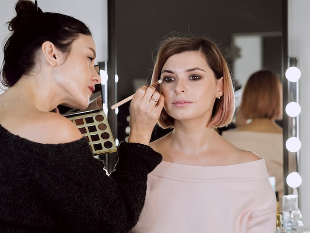 Künstler, der Make-up auf nettem Modell anwendet