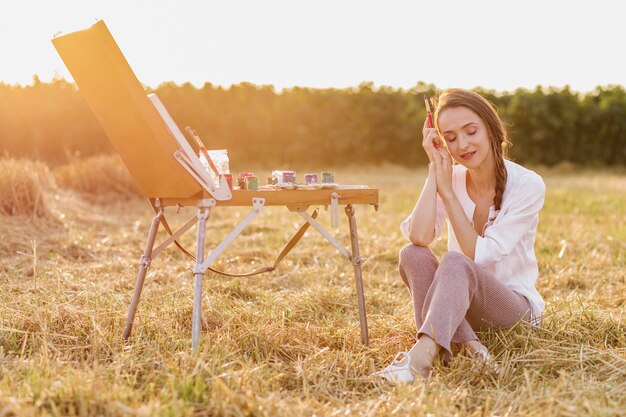 Künstlerische Frau, die auf dem Gras sitzt