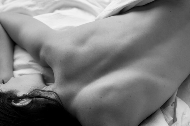 Künstlerische nackte Frau auf dem Bett