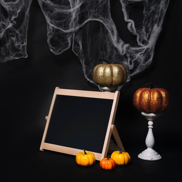 Kürbisse und Tafel in der Nähe von Halloween-Dekorationen