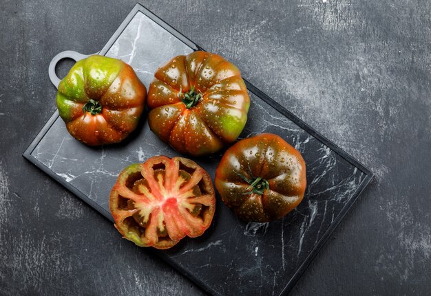 Kumato-Tomaten auf Grunge und Schneidebrettwand. flach liegen.