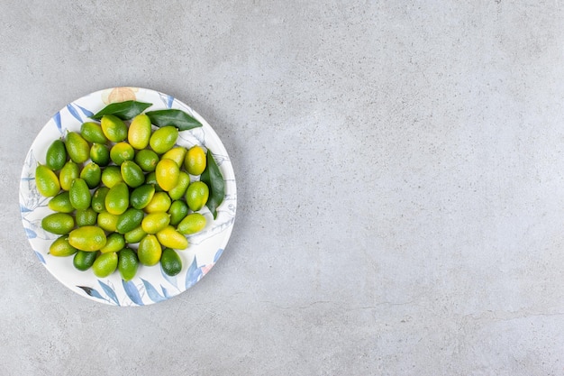 Kumquats und blätter auf einem teller im marmorhintergrund.