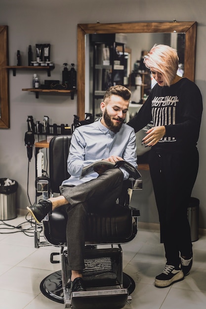 Kunde, der dem Friseur Zeitschrift zeigt