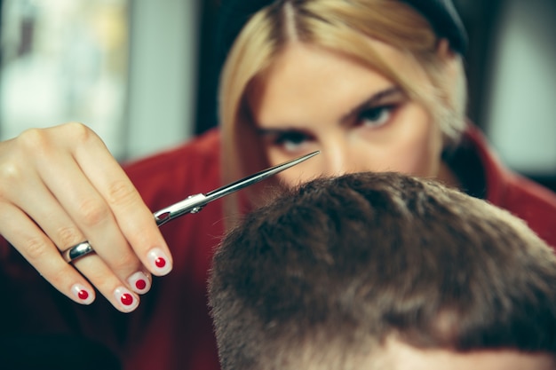 Kunde während der Bartrasur im Friseursalon. Friseurin im Salon. Geschlechtergleichheit. Frau im Männerberuf. Hände schließen