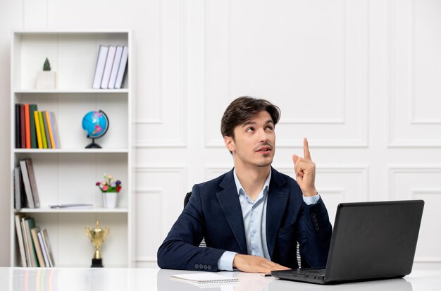 Kundenservice gutaussehender Kerl im Büroanzug mit dem Computer im Bürodenken