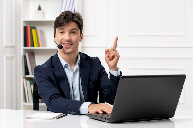 Kundenservice gutaussehender Typ mit Headset und Laptop im Anzug, der auf dem Computer tippt