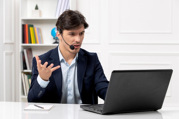 Kundenservice gutaussehender Typ mit Headset und Laptop im Anzug winkt bei Videoanrufen mit den Händen