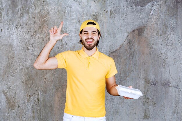 Kurier in gelber Uniform liefert eine Plastikbox zum Mitnehmen und sieht verwirrt und nachdenklich aus