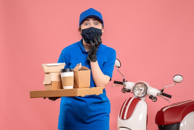 Kurierin der Vorderansicht mit Lieferung Kaffee und Essen auf rosa Pandemie Arbeit Lieferung Covid-Uniform Job Service