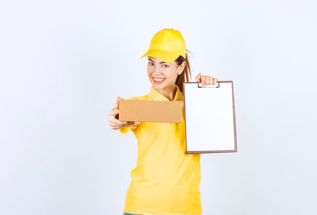 Kurierin in gelber Uniform liefert das Papppaket und bittet um Unterzeichnung der Liste.