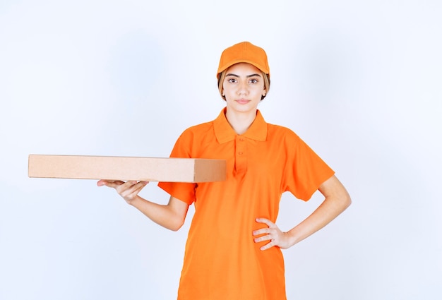 Kurierin in orangefarbener Uniform, die einen Karton liefert