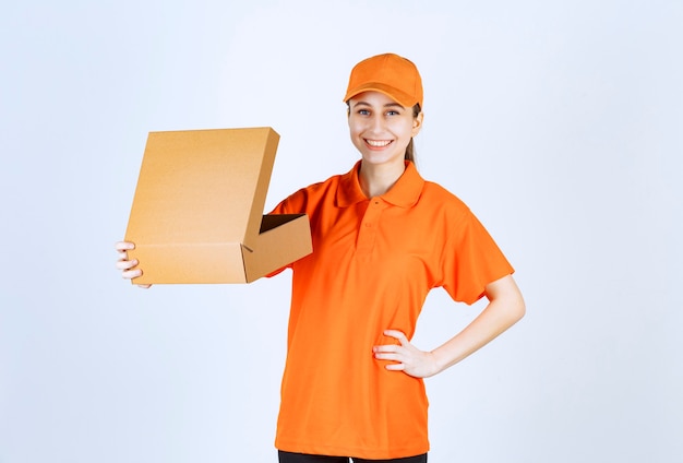 Kurierin in orangefarbener Uniform, die einen offenen Karton hält