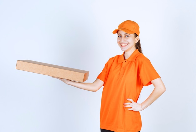 Kurierin in orangefarbener Uniform mit einer Pizzaschachtel zum Mitnehmen