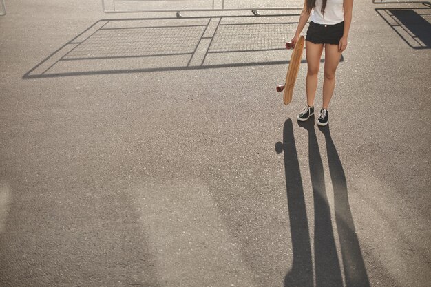 Kurzes Skater-Mädchen in Shorts, Turnschuhe beim Skateboarden