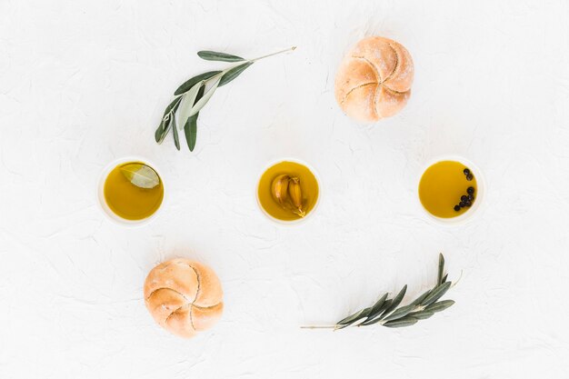 Öl der Olive, des Knoblauchs und des schwarzen Pfeffers in der Schüssel mit zwei Brötchen