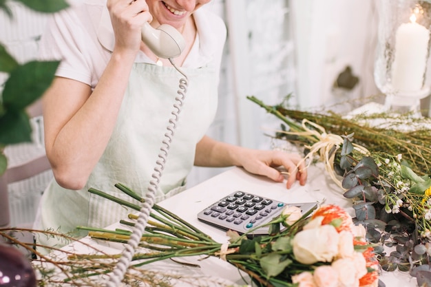 Lachende Arbeitskraft, die am Telefon im Shop spricht