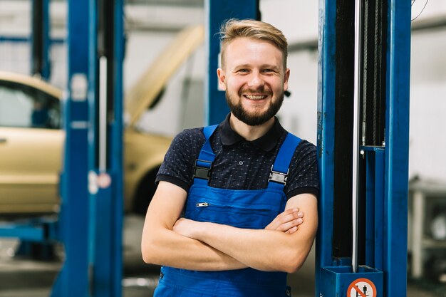 Lachende Automechaniker, die Hände kreuzen